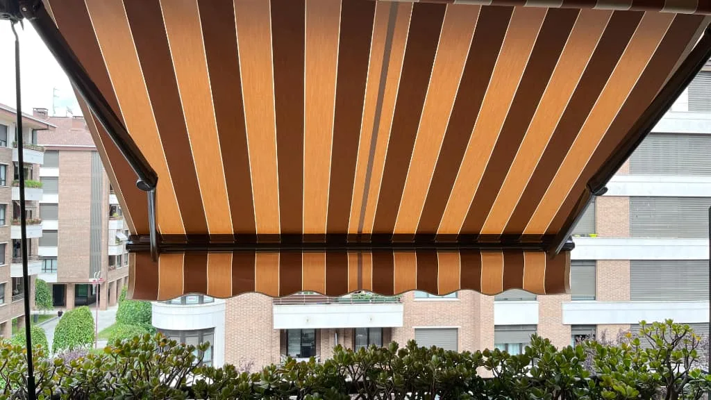 toldo rayas marrones balcon edificio residencial - Toldos Itzalki — Itzalki Toldoak — Zarautz Toldo extensible a rayas marrones instalado en balcón de edificio residencial