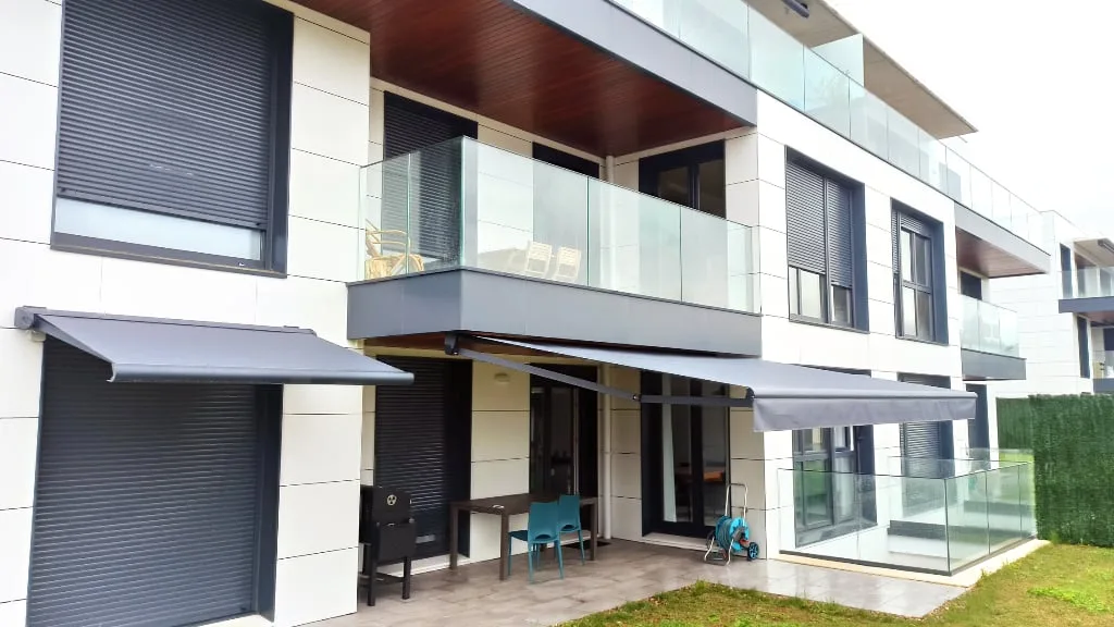 toldos extensibles terraza vivienda moderna - Toldos Itzalki — Itzalki Toldoak — Zarautz Toldos extensibles en terraza de vivienda moderna con fachada blanca y persianas negras