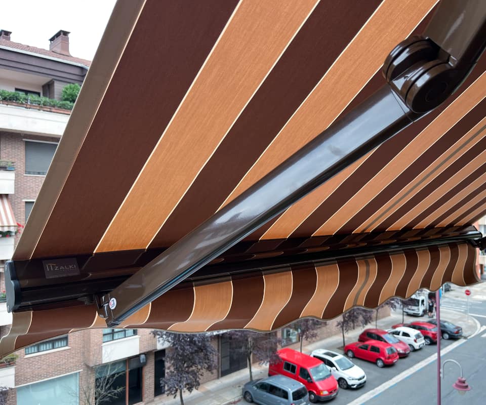 Hiri bateko balkoian instalatutako marradun kutxa-toldo bat, Itzalki Toldoak enpresak Zarautzen (Gipuzkoa, Euskal Herria) jarritakoa, Usurbilen ere jarduten duena