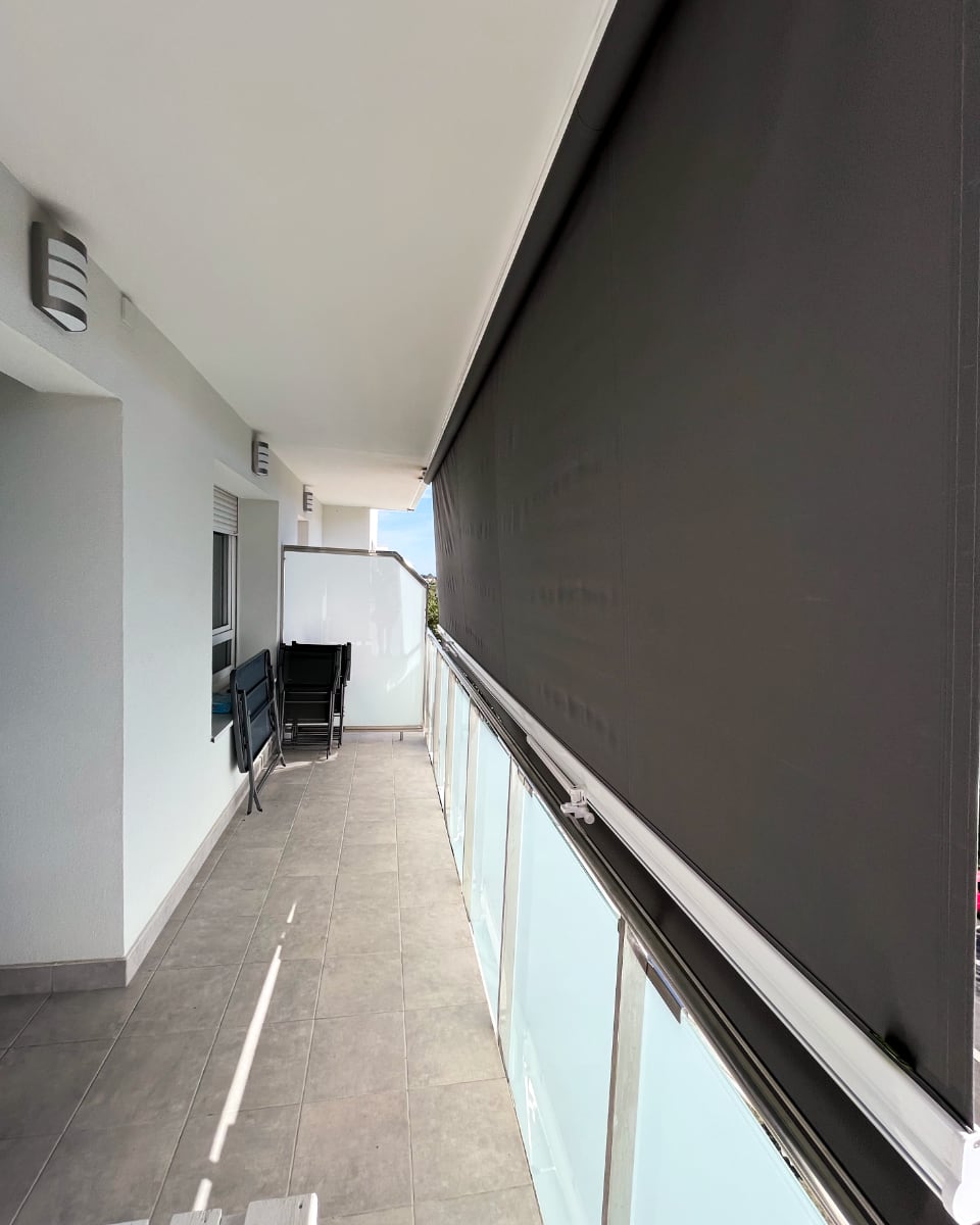 Screen motako toldo bertikal beltza, beirazko terraza batean instalatua, Itzalki Toldoak enpresak Zarautzen (Gipuzkoa, Euskal Herria) jarritakoa, Lasarte-Orian ere zerbitzua eskaintzen duena