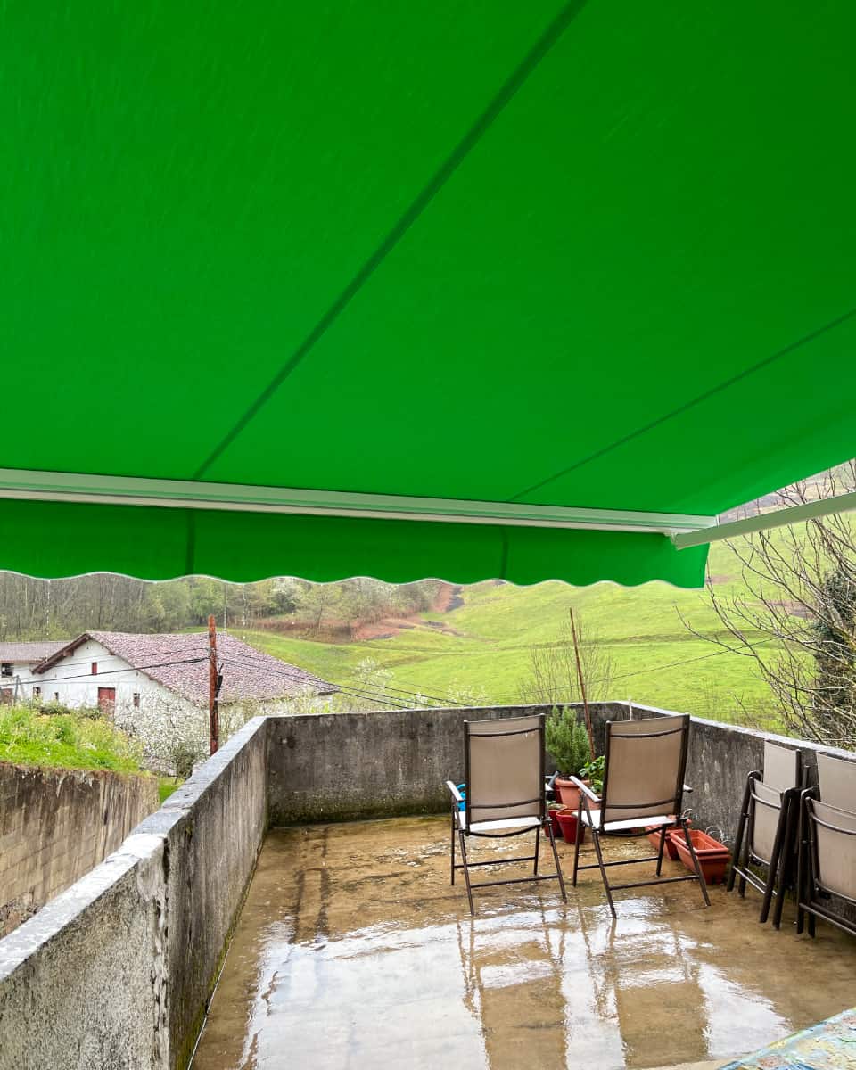 Toldo hedagarri berdea, landa-inguruneko terraza batean instalatua, Itzalki Toldoak enpresak Zarautzen (Gipuzkoa, Euskal Herria) egindakoa, Tolosan ere jarduten duena