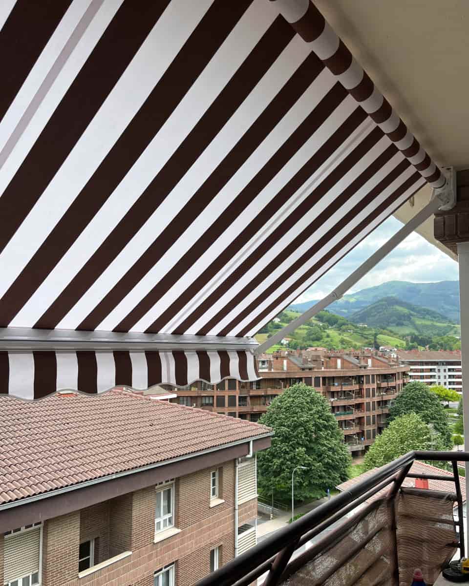 Marra zuri eta marroizko toldo hedagarria, eremu egoitza eta menditsura begira, Itzalki Toldoak enpresak Zarautzen (Gipuzkoa, Euskal Herria) instalatua, Irunen ere jarduten duena