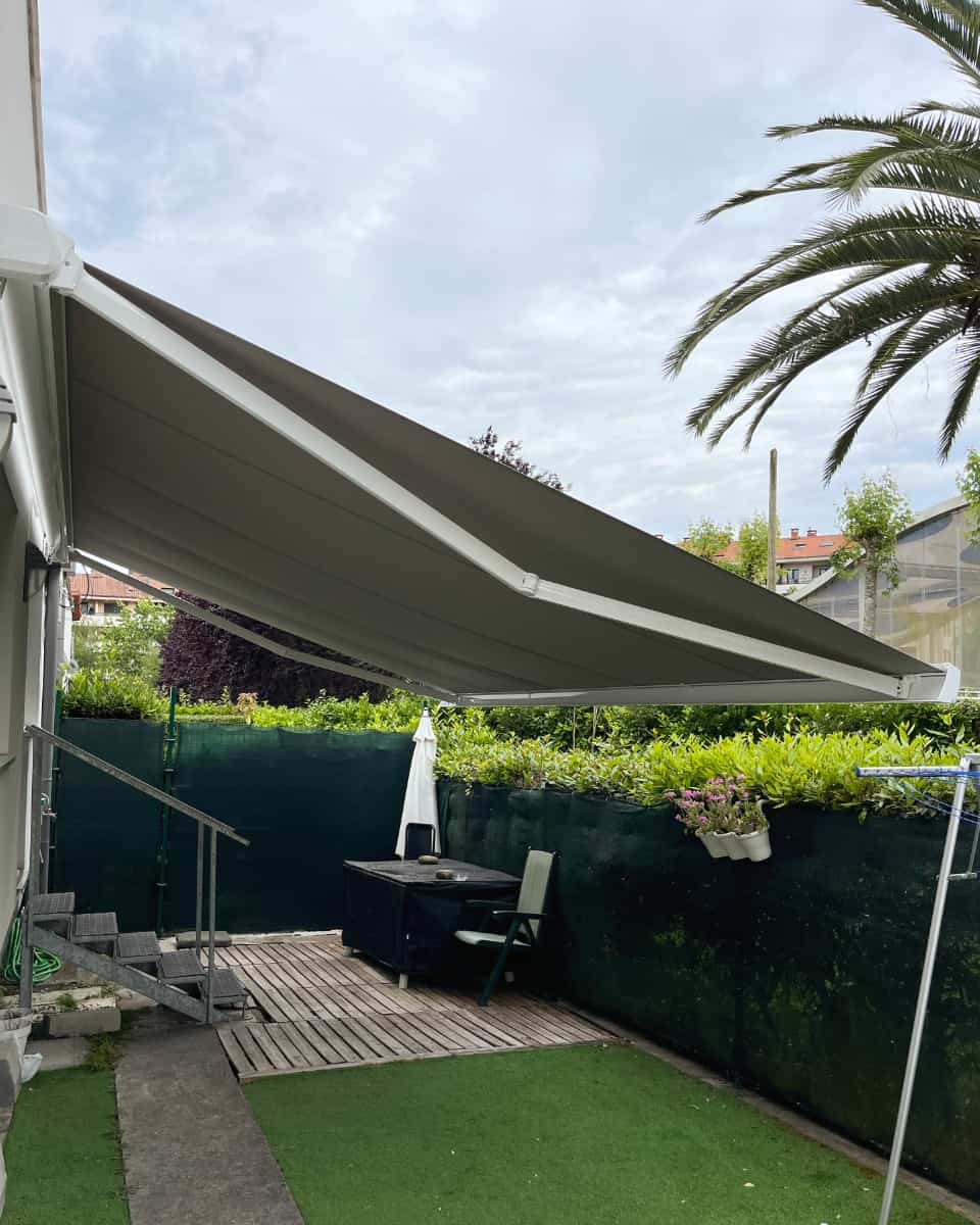 Kolore beixako toldo hedagarri soila, etxebizitza baten atzeko lorategian instalatua, Itzalki Toldoak enpresak Zarautzen (Gipuzkoa, Euskal Herria) egindakoa, Urretxun ere zerbitzua eskaintzen duena