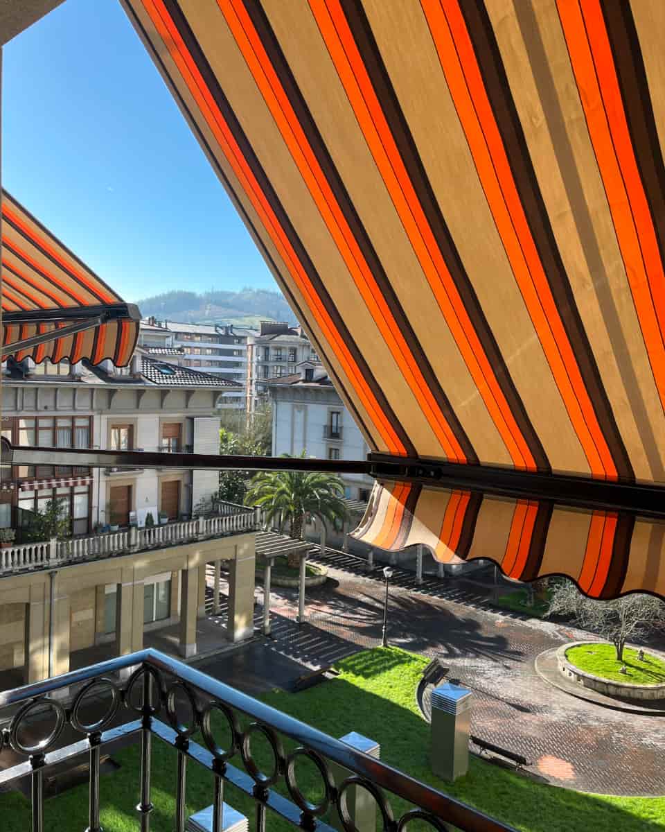 Marra laranjadun eta marroidun toldoa, burdinazko barandadun balkoi batean instalatua, Itzalki Toldoak enpresak Zarautzen (Gipuzkoa, Euskal Herria) jarritakoa, Beasainen ere jarduten duena