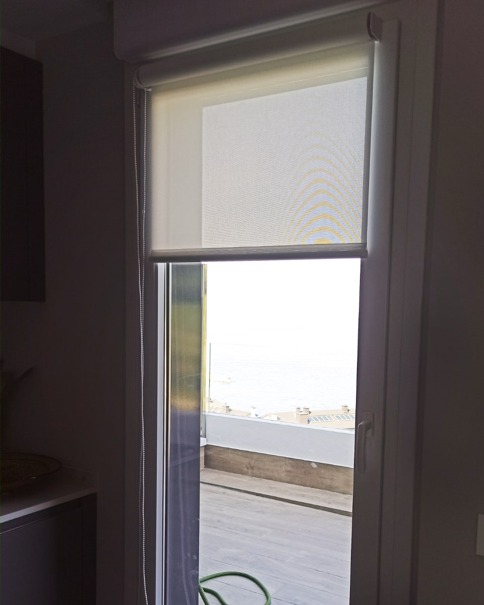 Estore enrollable blanco en puerta con vista al mar, instalado por Itzalki Toldoak en Zarautz, Guipúzcoa, País Vasco, con servicio también en San Sebastián