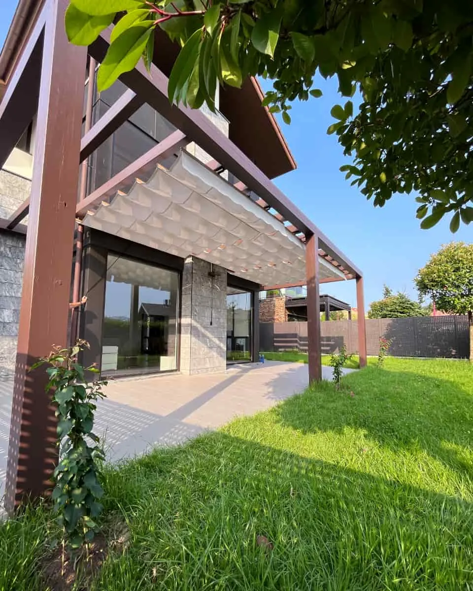 Kanpoko pergola, uhindun teloi motako oihalarekin, lorategidun familia bakarreko etxebizitza batean instalatua, Itzalki Toldoak enpresak Zarautzen (Gipuzkoa, Euskal Herria) egindakoa, Tolosan ere jarduten duena