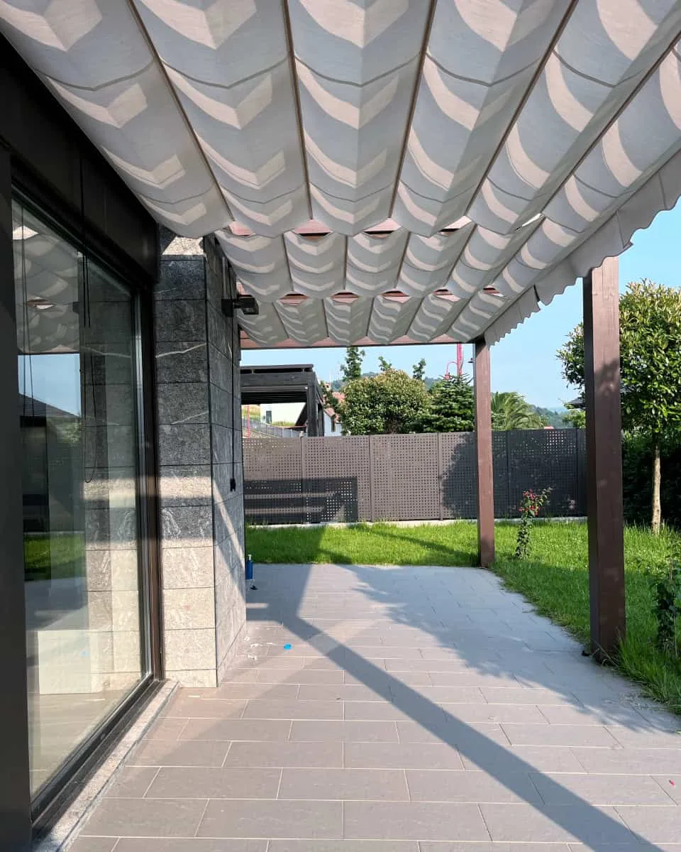 Oihal uhinduneko pergola bat, lorategidun etxebizitza ondoan dagoen terraza batean instalatua, Itzalki Toldoak enpresak Zarautzen (Gipuzkoa, Euskal Herria) egindakoa, Eibarren ere jarduten duena